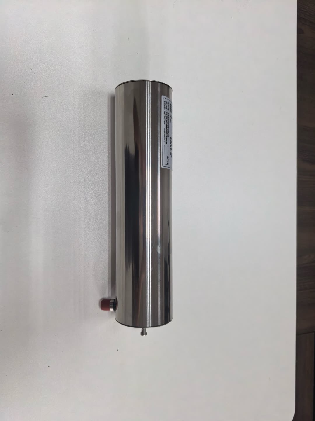Household kitchen fire suppression system cylinder standing upright — polished stainless body with red thermal bulb at the base